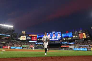 Aaron Judge injury Yankees: Baseball player in white uniform runs toward dugout