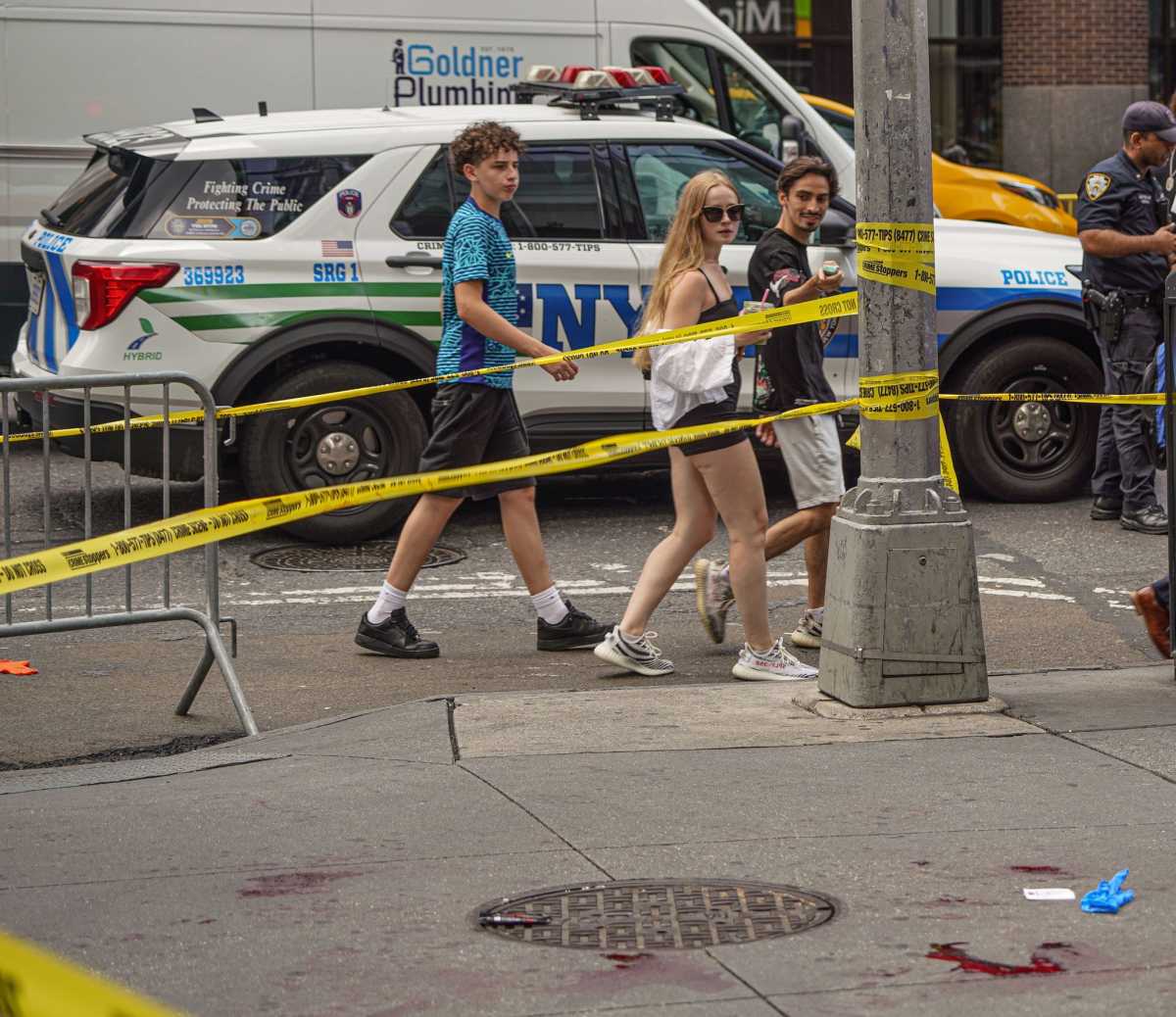people looking at blood-covered crime scene and yellow police tape in Midtown after stabbing