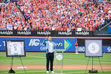 David Wright: Man in blue suit stands on baseball field and gives speech to fans.