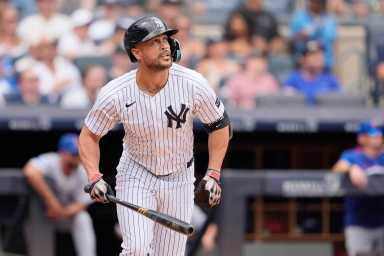 man in yankee uniform and helmet holding bat after hitting home run