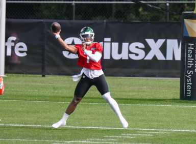 Justin Fields Jets: Football player with green helmet and red jersey throws football