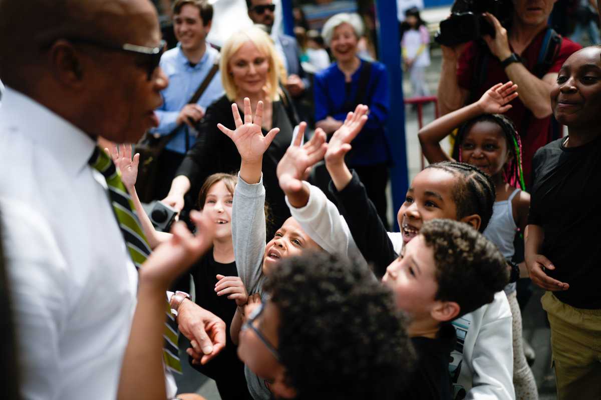 Group of kids smiling and waving at man at after-school program