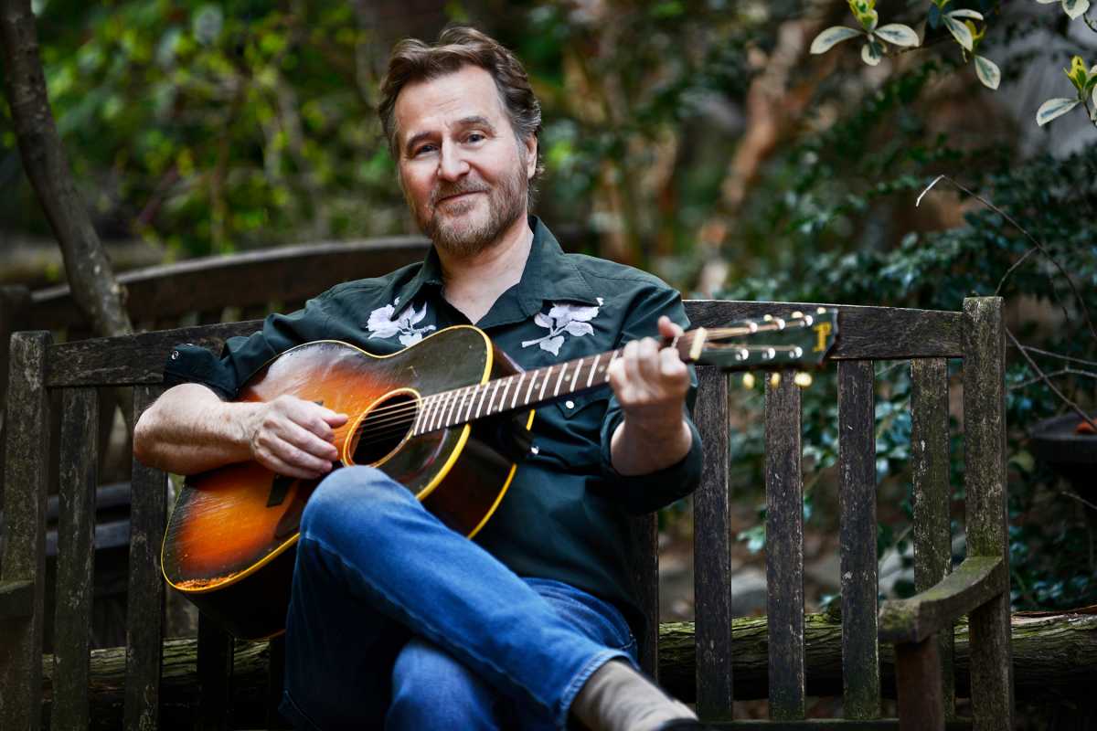 man in garden picking guitar rollo white