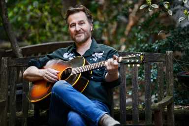 man in garden picking guitar rollo white