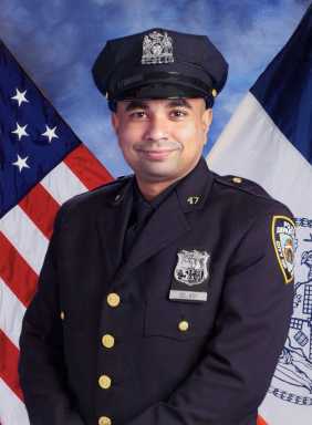 police officer smiling in front of American and New York flag