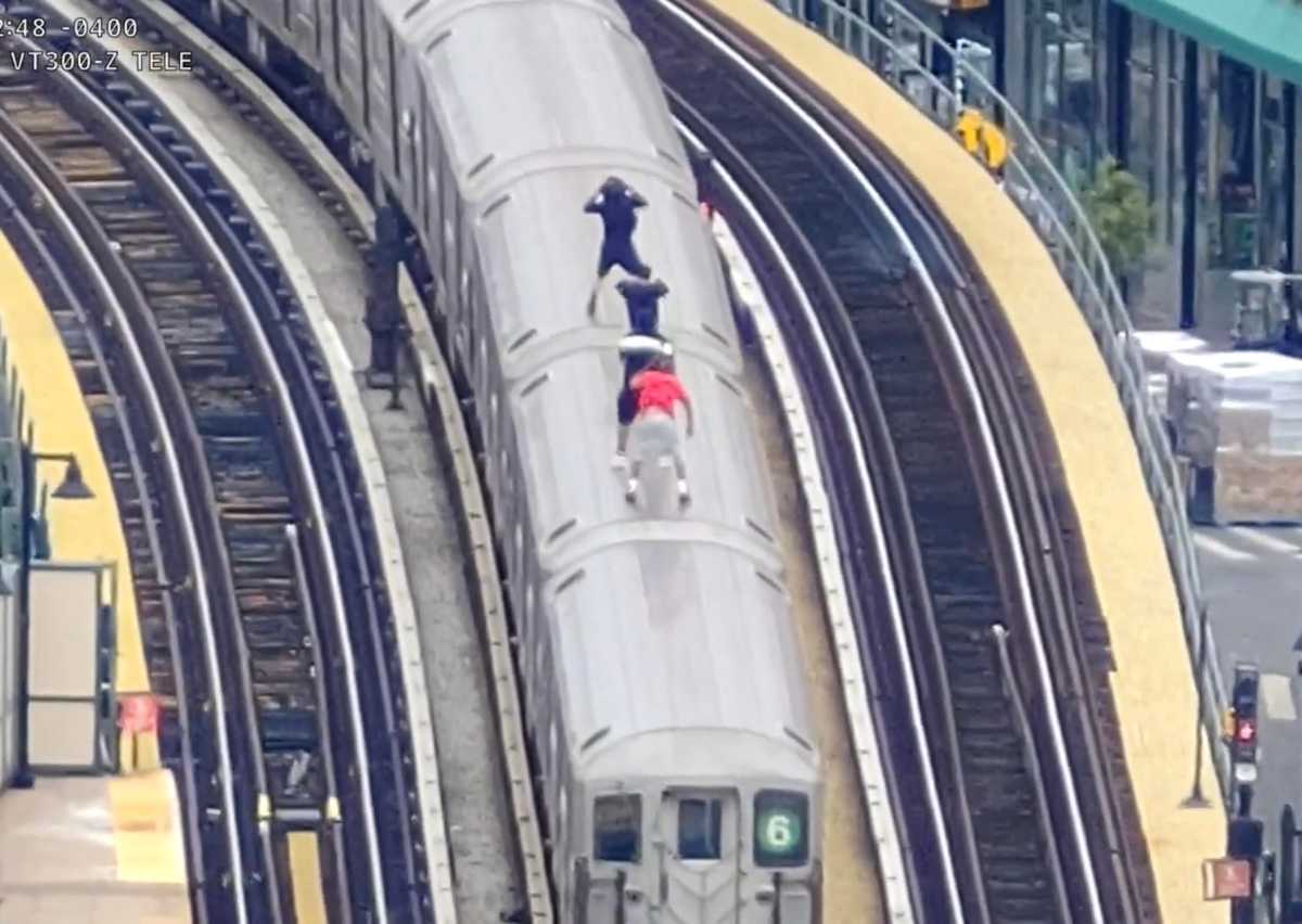 drone footage shows four people riding on top of moving subway car while subway surfing
