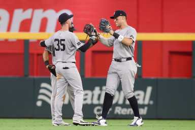 Aaron Judge Cody Bellinger Yankees: 2 baseball players high five in outfield