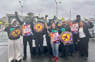 Workers from 2 NYC airports rally for better working conditions during extreme heat 19 people holding signs in the rain at an airport