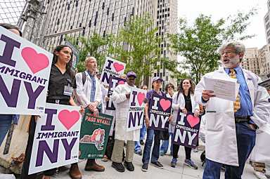 doctors holding signs and wearing lab coats while protesting ICE treatment of immigrants