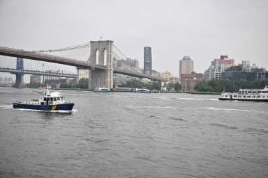 a police boat in in the east river by the Brooklyn Bridge.