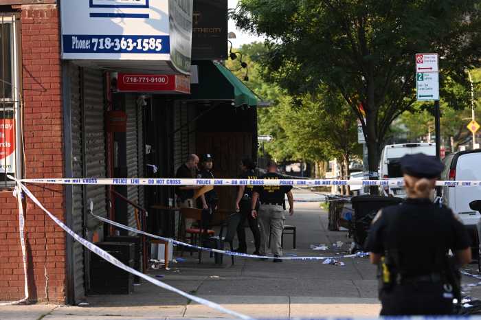 police officer standing with police tape at scene of brooklyn mass shooting