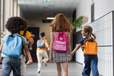 Joyful children rush down the hallway, backpacks bouncing, eager to learn