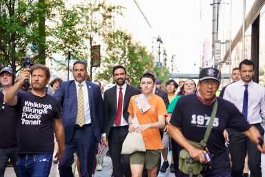 a group of people walking on a Midtown Manhattan sidewalk wearing suits and casual clothes