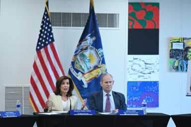 MTA board approves $2 billion contract to extend Second Avenue Subway into East Harlem - a 'long overdue' project 26 a woman and man sitting at a table in front of the American flag and NYS flag