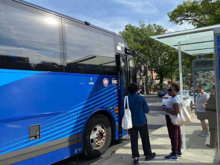On the Express: Queens express buses offer a smooth ride to Manhattan, for the most part 2 people at a bus stop as a bus arrives